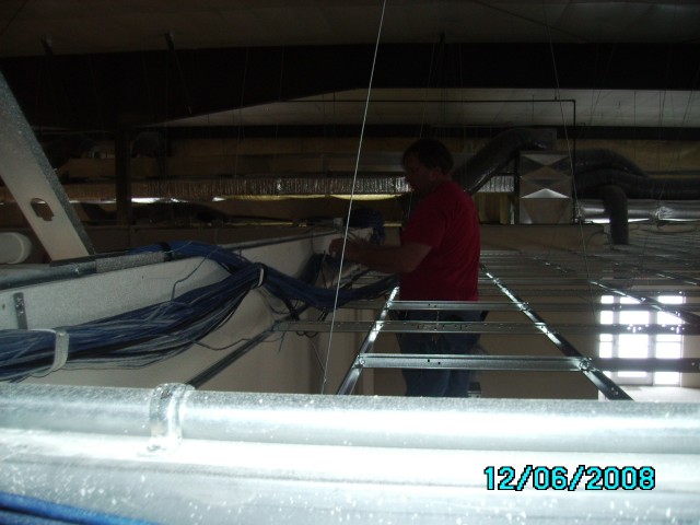 Dan Vorwald hangs cabling above the ceiling tile.  